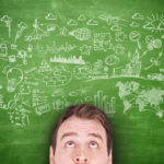Man with green blackboard above him with business related drawings